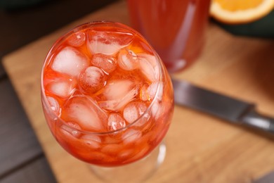 Photo of Aperol spritz cocktail and ice cubes in glass on wooden table, above view