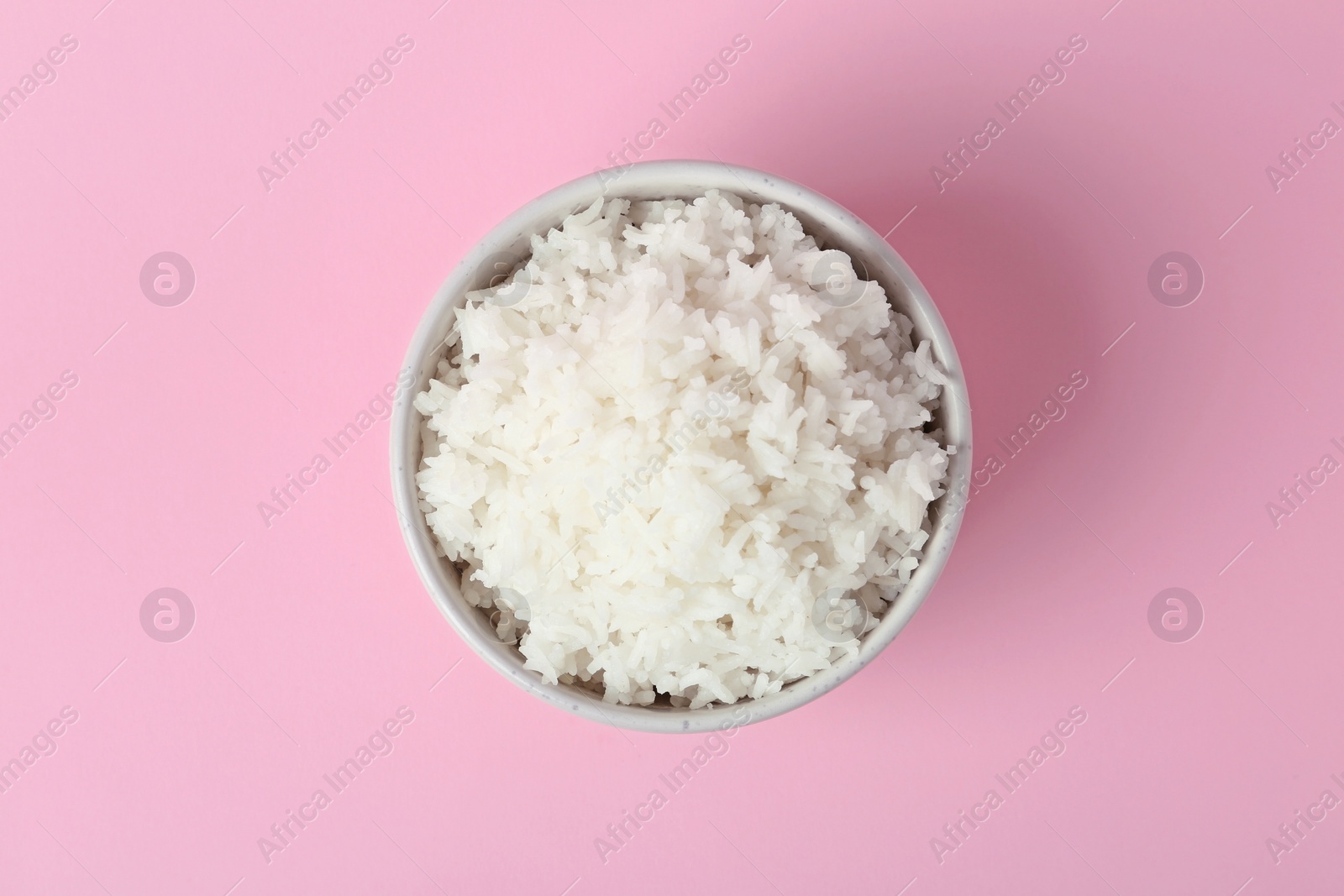 Photo of Bowl of boiled rice on color background, top view