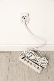 Photo of Extension cord with power plug in socket indoors. Electrician's professional equipment