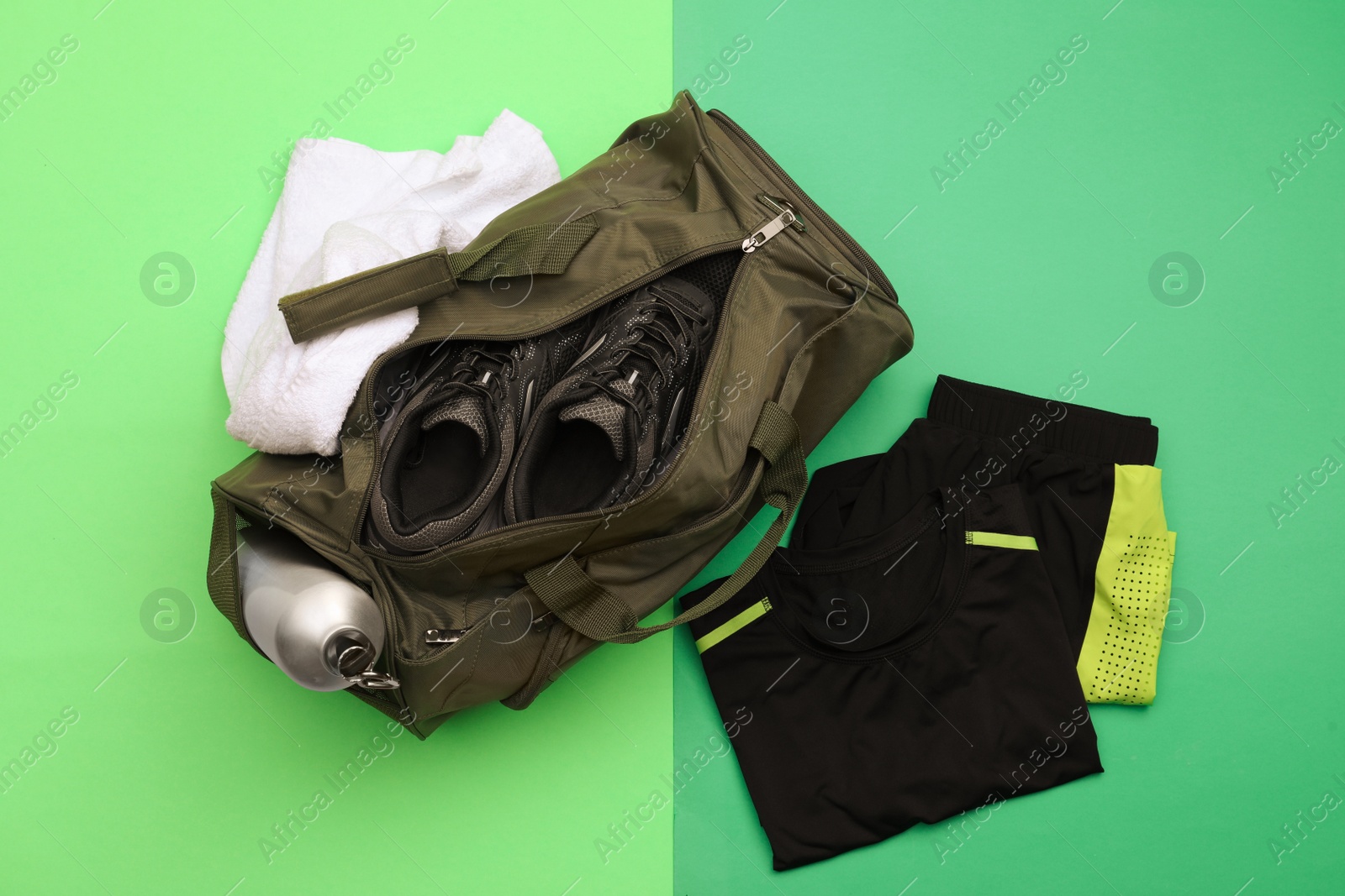 Photo of Gym bag and sports equipment on green background, flat lay