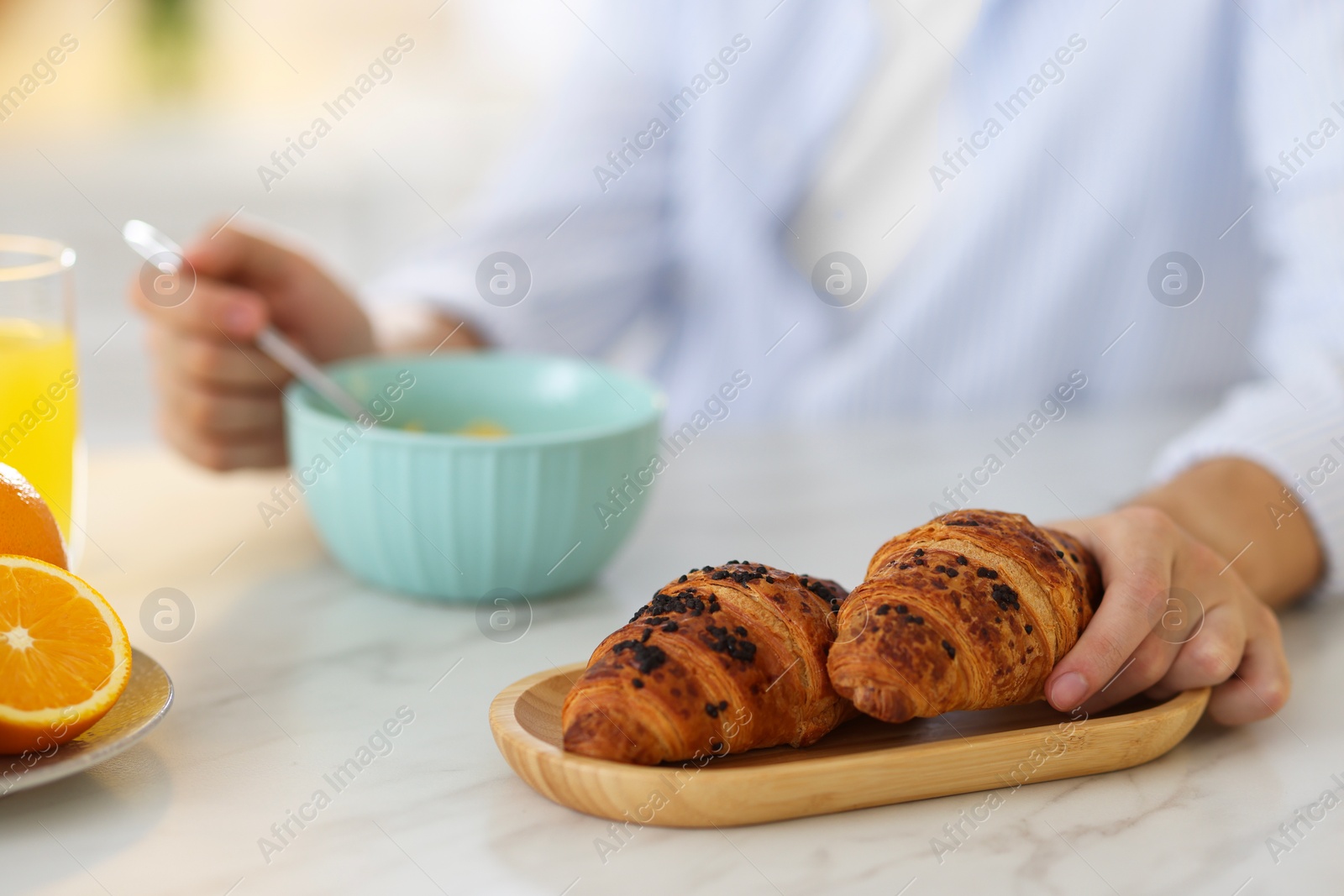 Photo of Tasty breakfast. Man taking croissant at white marble table, closeup