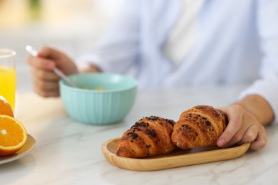 Photo of Tasty breakfast. Man taking croissant at white marble table, closeup