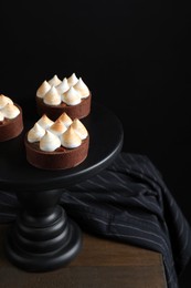 Photo of Delicious salted caramel chocolate tarts on wooden table against dark background