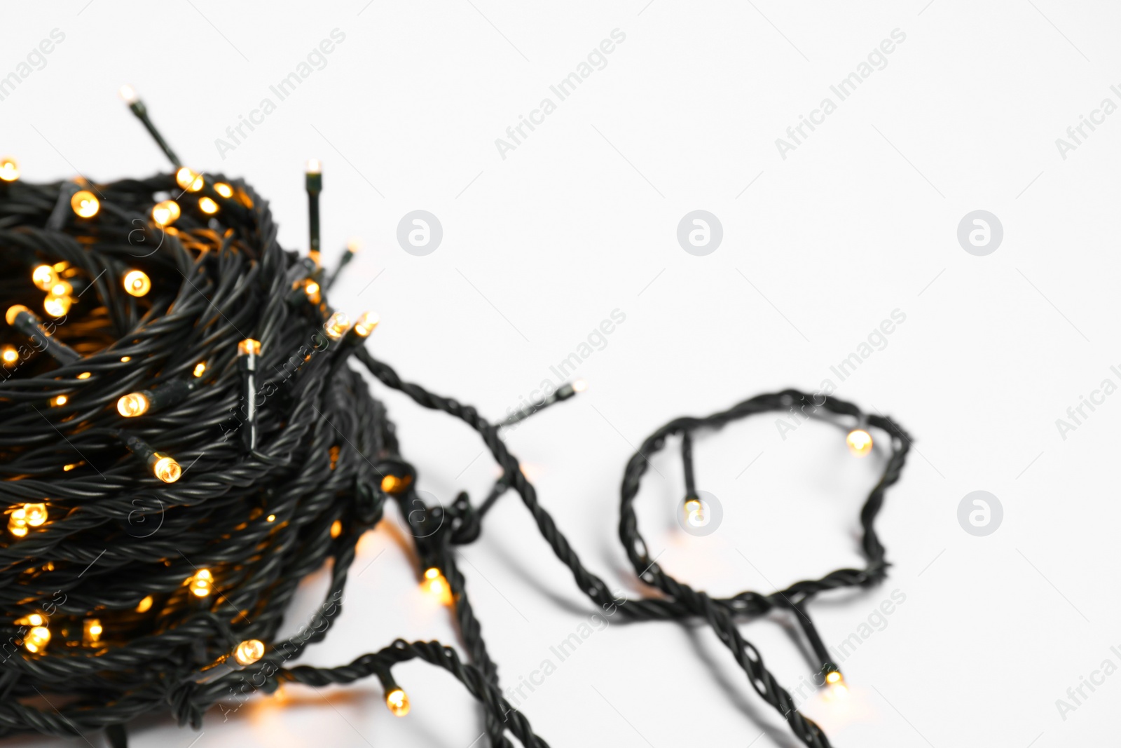 Photo of Beautiful Christmas lights on white background, closeup