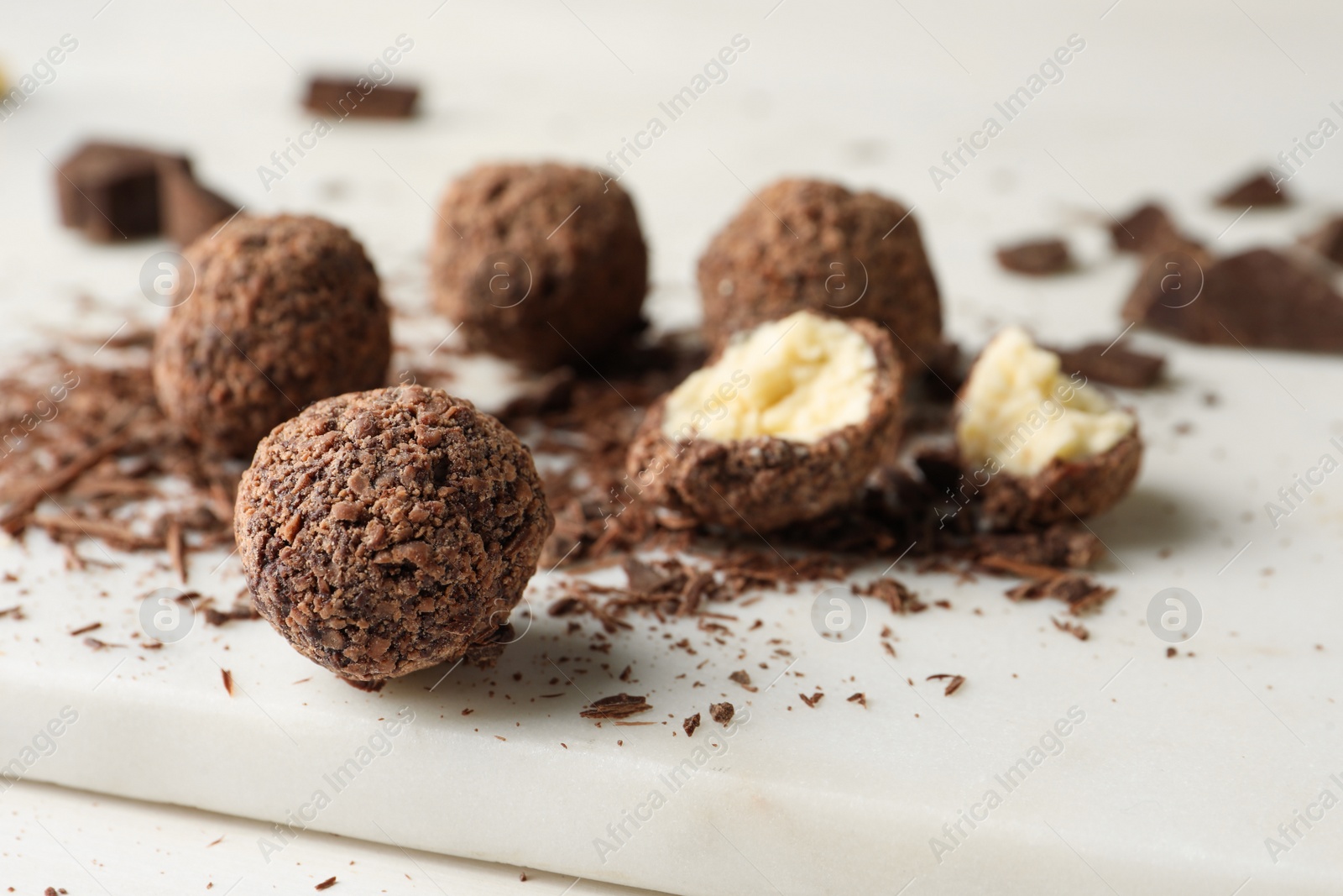 Photo of Many delicious chocolate truffles on white board, closeup. Space for text