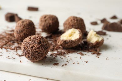 Photo of Many delicious chocolate truffles on white board, closeup. Space for text