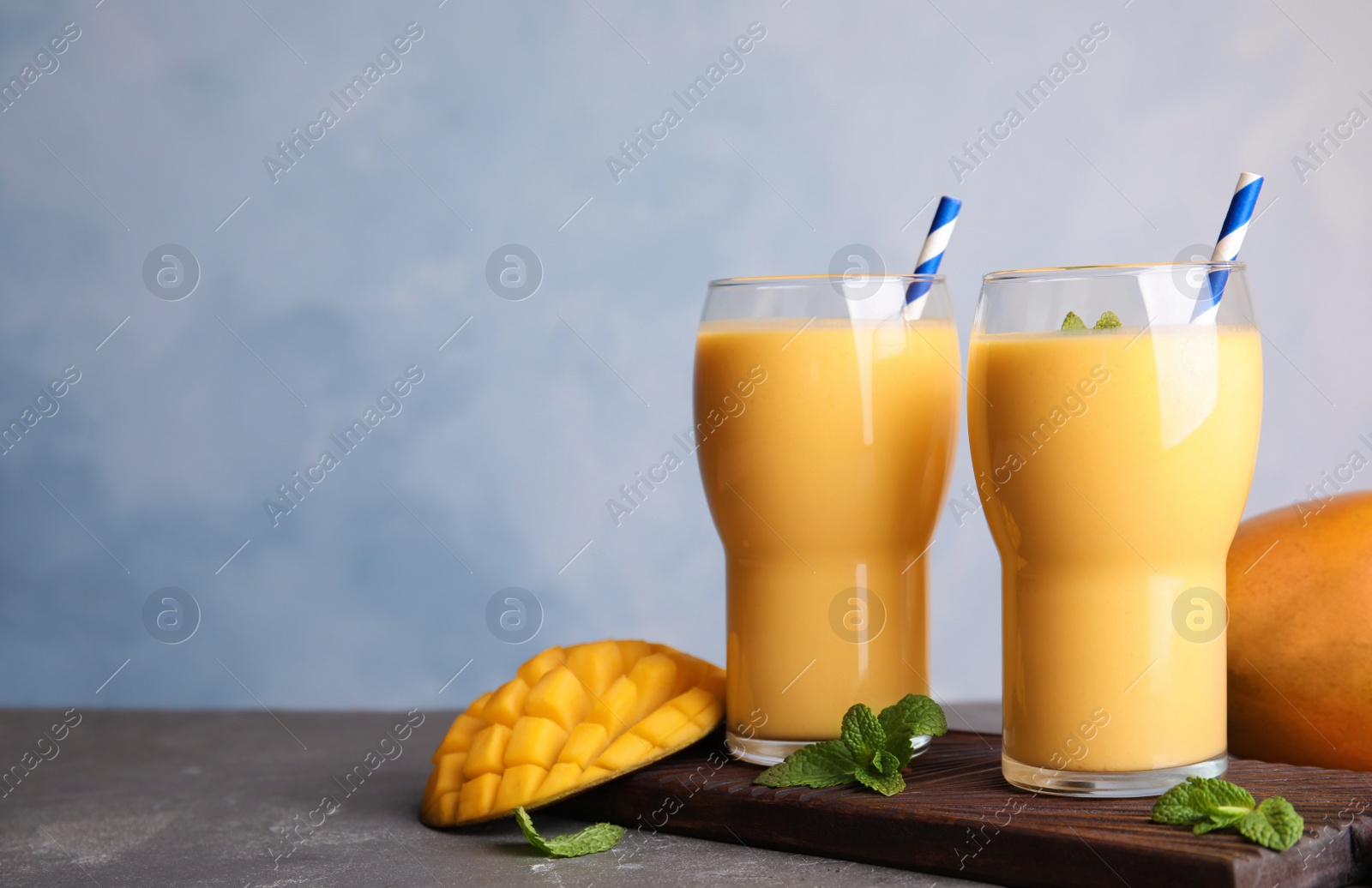 Photo of Glasses of fresh mango drink and fruits on table. Space for text