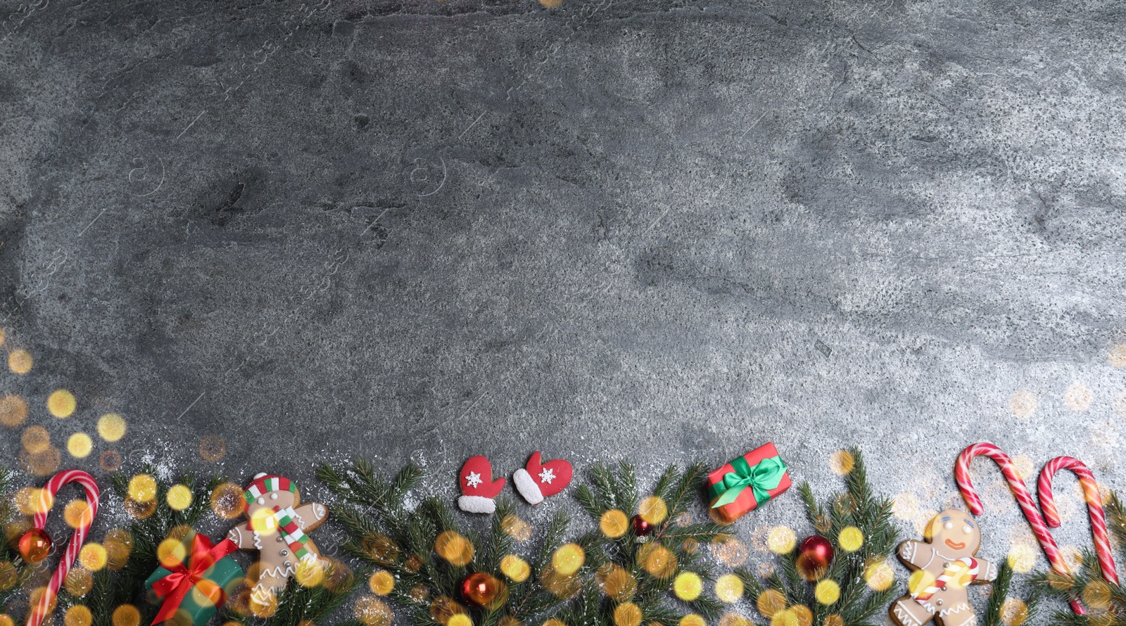 Photo of Christmas greeting card with space for text. Flat lay composition of fir tree branches and festive decor on grey background