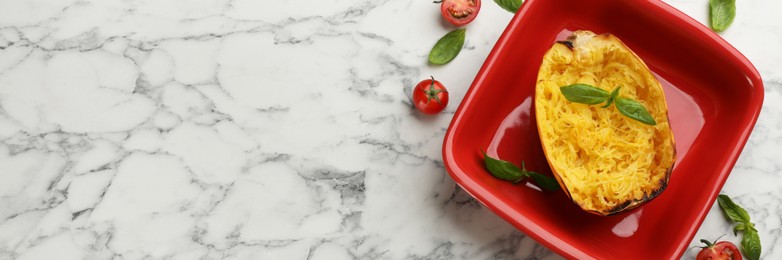 Half of cooked spaghetti squash in baking dish, tomatoes and basil on white marble table, flat lay. Banner design with space for text