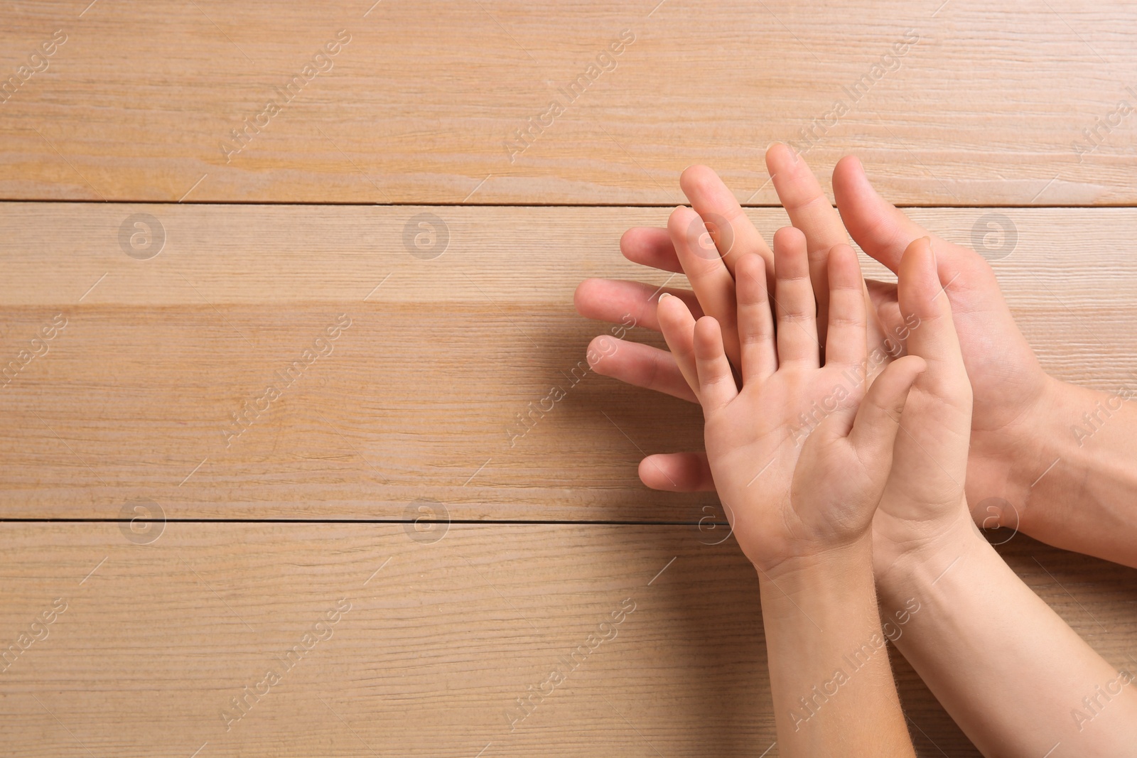 Photo of Family holding hands together on wooden background, top view. Space for text