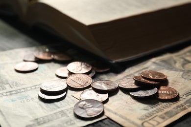 Photo of Donate and give concept. Coins, dollar banknotes and Bible on dark table, selective focus
