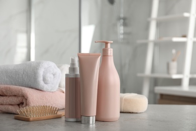 Photo of Different hair care products, towels and brush on table in bathroom