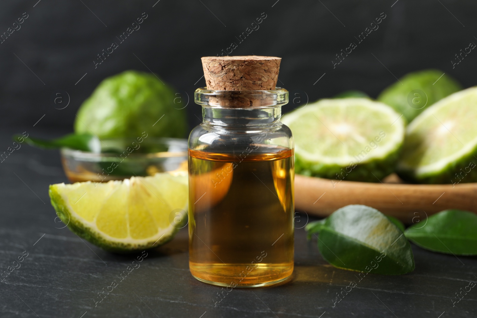 Photo of Bottle of bergamot essential oil on dark table, closeup