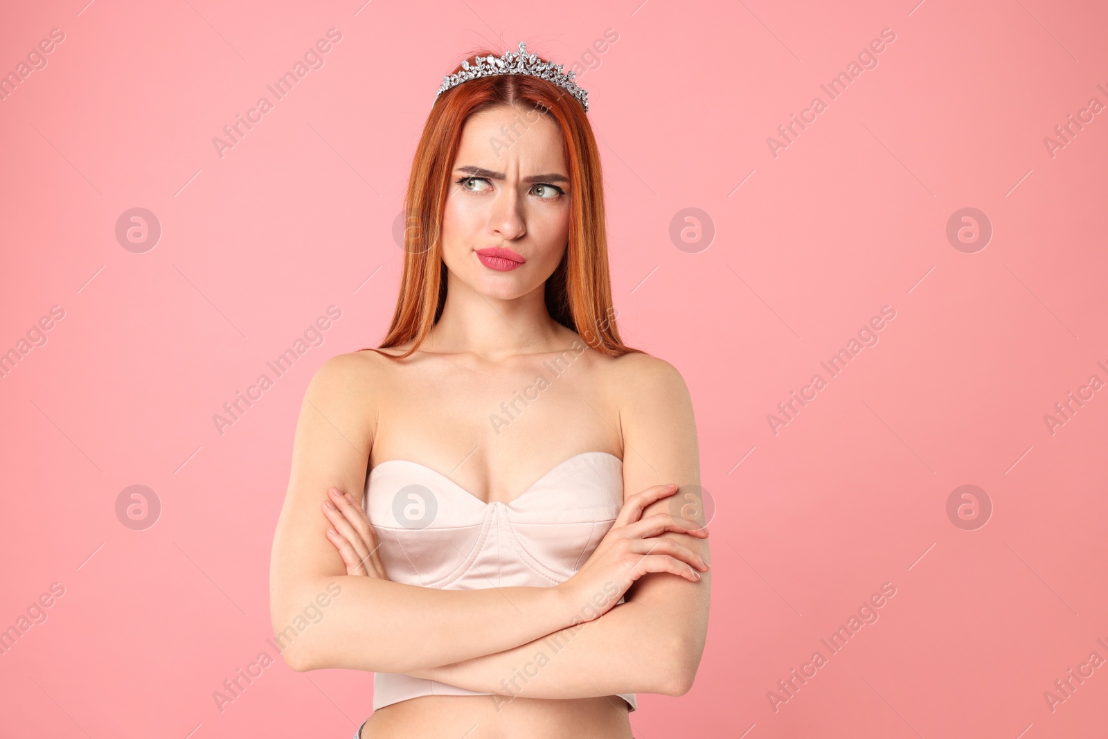 Photo of Emotional young woman with tiara on pink background