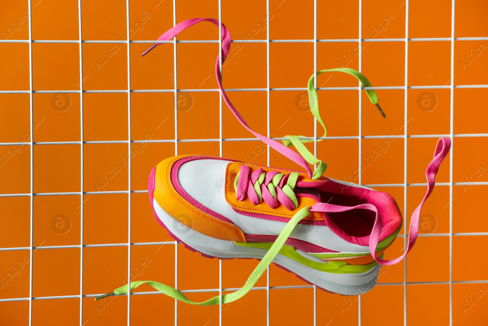 Photo of Stylish presentation of trendy sneaker on orange background