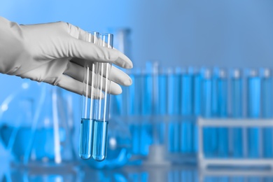 Scientist holding test tubes with liquid for analysis in laboratory. Space for text