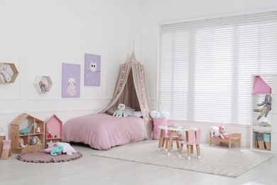 Photo of Cute child's room interior with toys and modern furniture