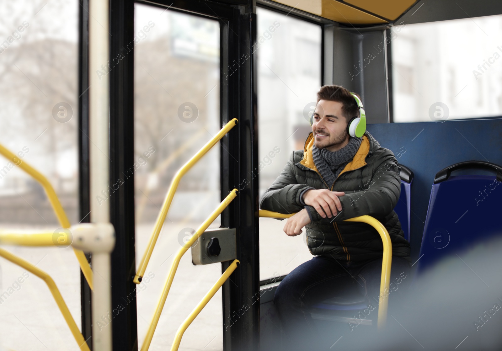 Photo of Young man listening to music with headphones in public transport