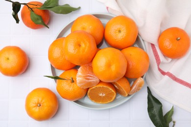 Photo of Fresh juicy tangerines on white tiled table, flat lay