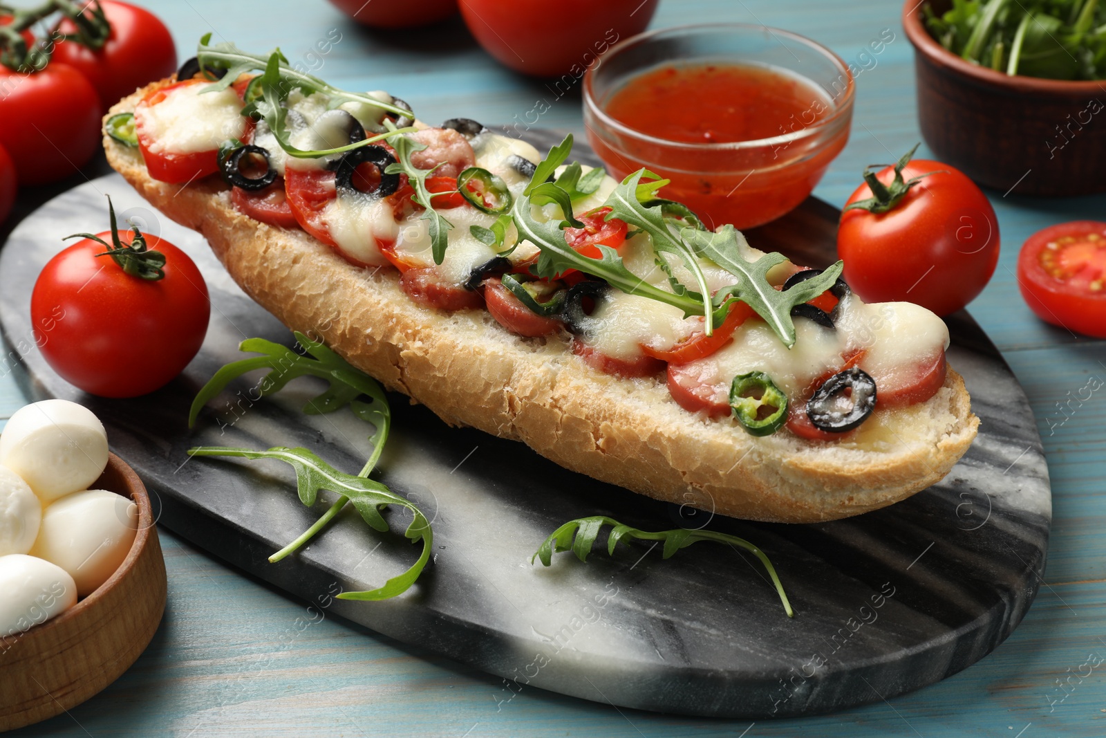 Photo of Tasty pizza toast and ingredients on light blue wooden table