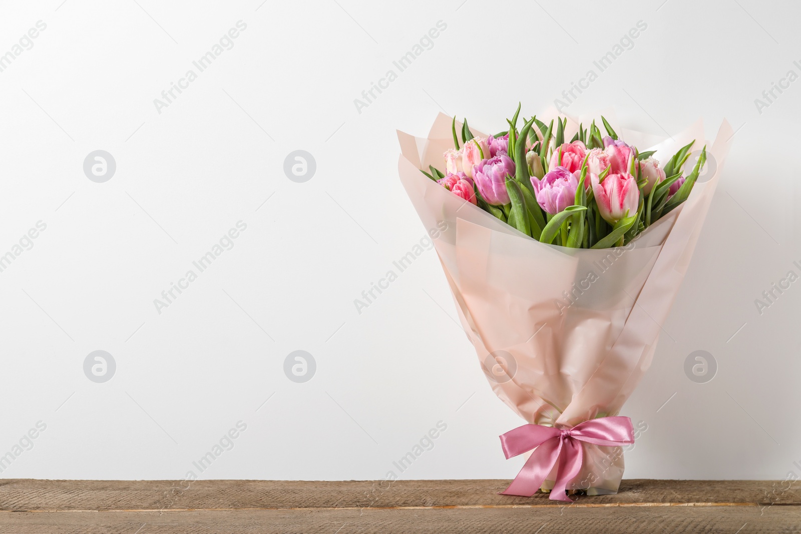 Photo of Bouquet of beautiful tulips on wooden table. Space for text