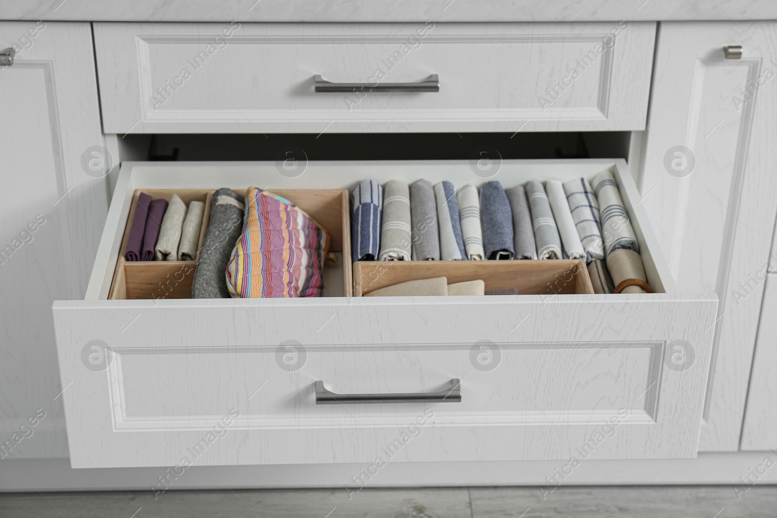 Photo of Open drawer with different textiles in kitchen