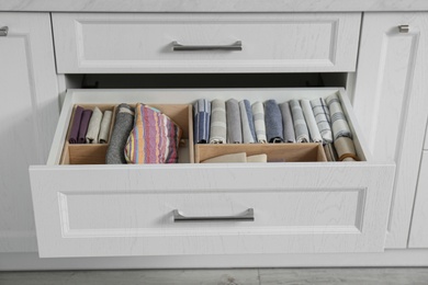 Photo of Open drawer with different textiles in kitchen