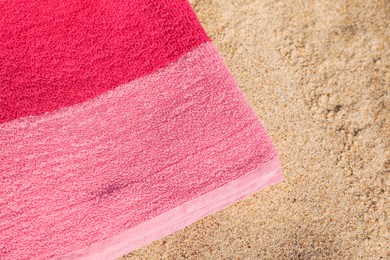 Soft pink beach towel on sand, closeup. Space for text