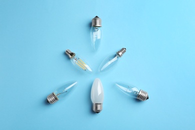 Different lamp bulbs on light blue background, flat lay