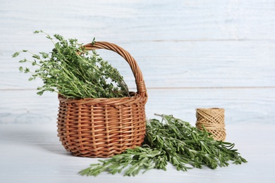 Rosemary with thyme in wicker basket and twine on wooden table. Aromatic herbs