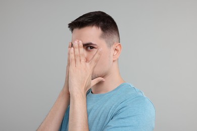 Embarrassed man covering face with hands on grey background