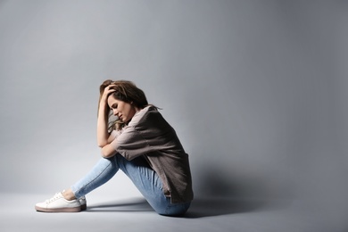 Photo of Lonely depressed woman sitting on grey background