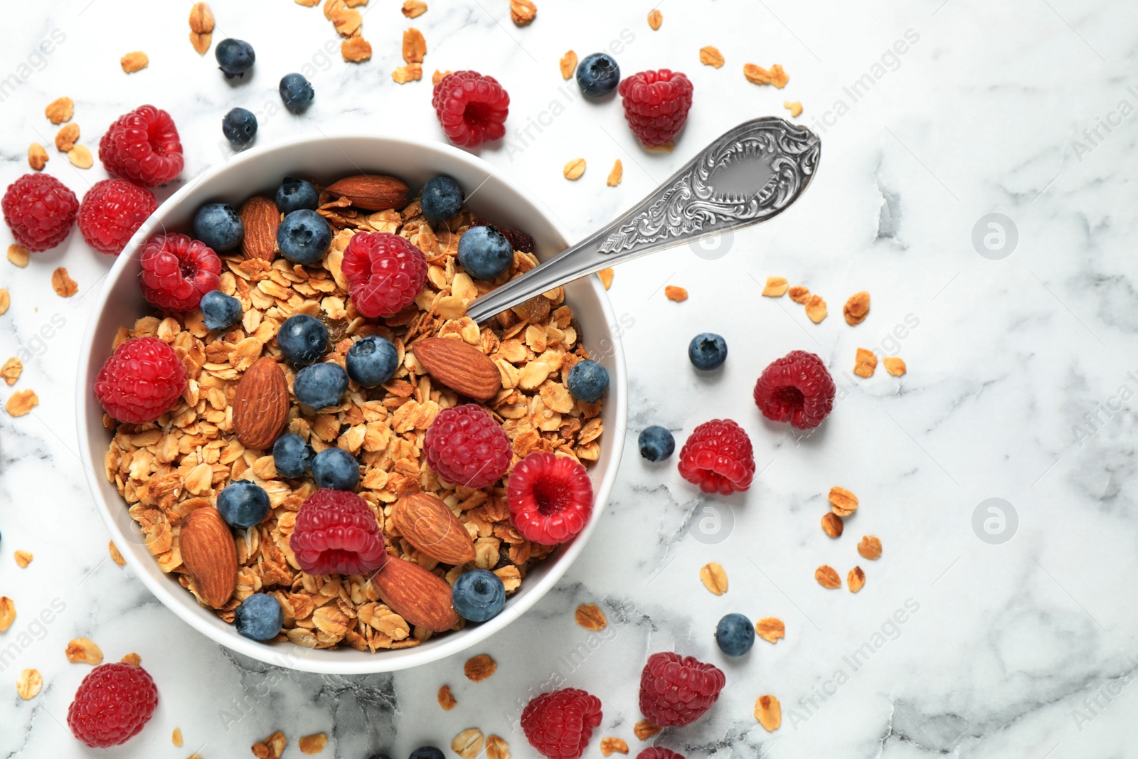 Photo of Tasty homemade granola with berries on white marble table, top view. Healthy breakfast