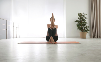 Photo of Woman practicing eagle asana in yoga studio. Garudasana pose