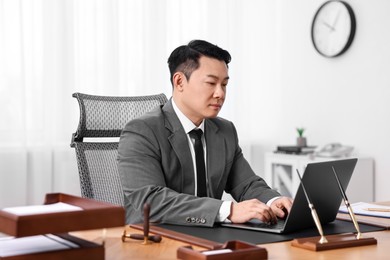 Notary working with laptop at wooden table in office