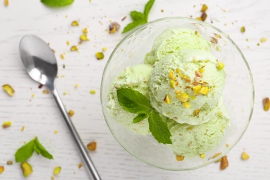 Delicious green ice cream served in dessert bowl on white wooden table, top view