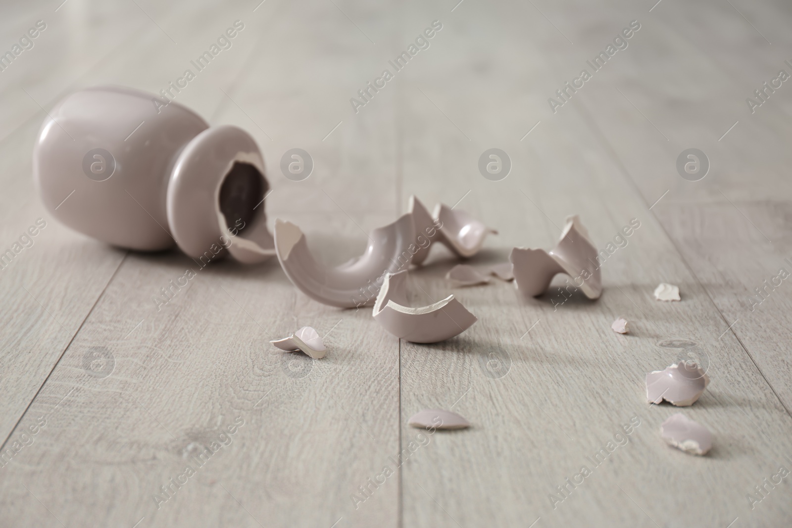 Photo of Broken pink ceramic vase on wooden floor