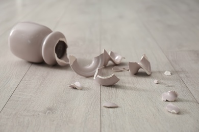 Broken pink ceramic vase on wooden floor