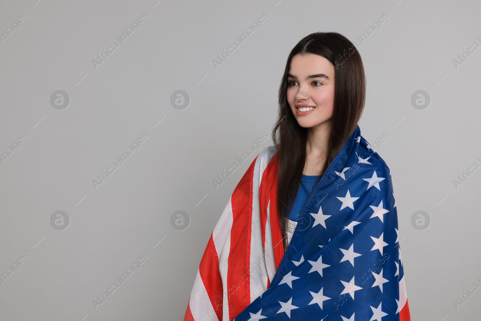 Photo of 4th of July - Independence Day of USA. Happy girl with American flag on grey background, space for text