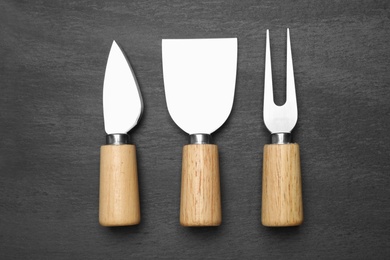 Photo of Cheese knives and fork on black background, flat lay