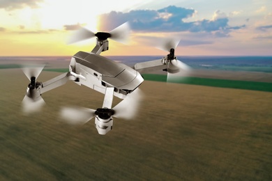 Image of Modern drone flying over field at sunset. Aerial survey