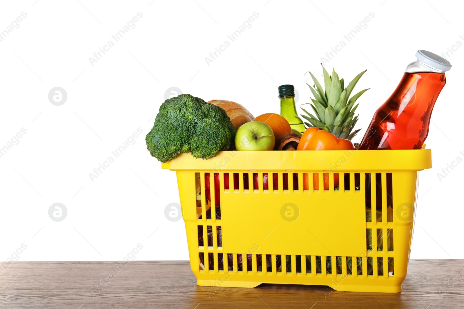 Photo of Shopping basket with grocery products on wooden table against white background. Space for text