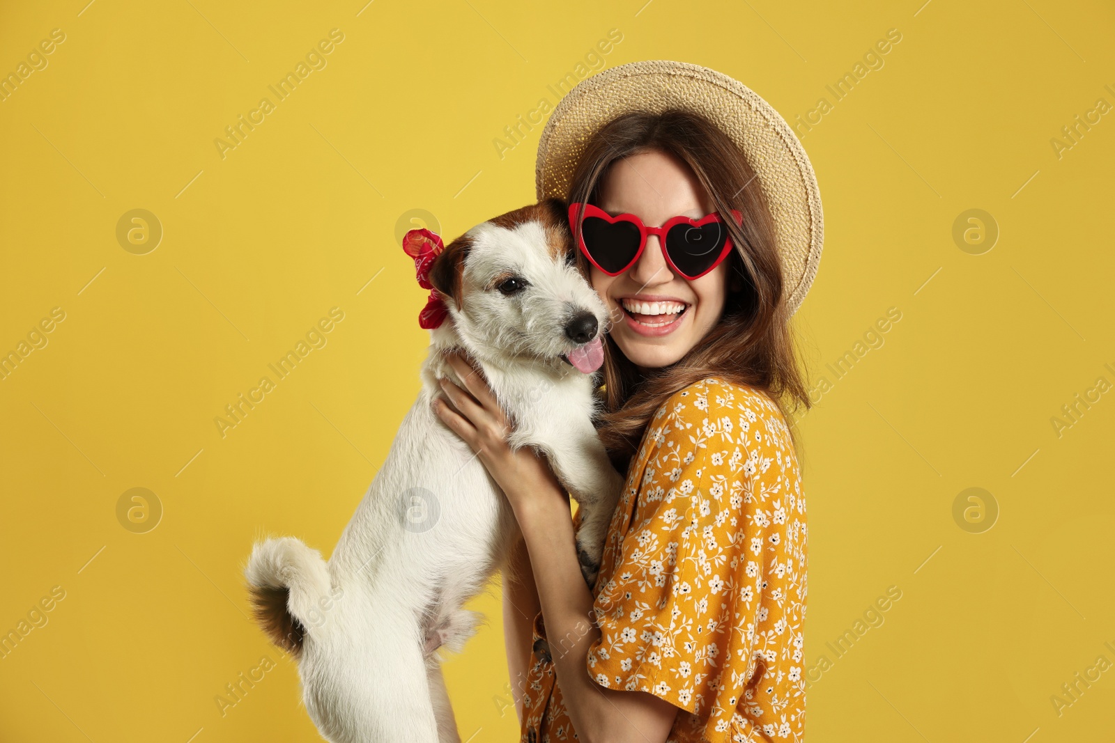 Photo of Young woman with her cute Jack Russell Terrier on yellow background. Lovely pet