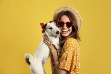 Young woman with her cute Jack Russell Terrier on yellow background. Lovely pet