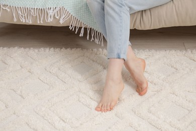 Woman sitting on sofa near beige carpet indoors, closeup. Space for text