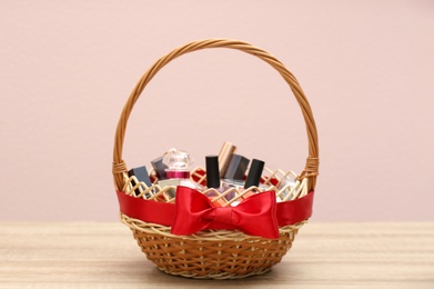 Photo of Wicker gift basket with cosmetic products on wooden table