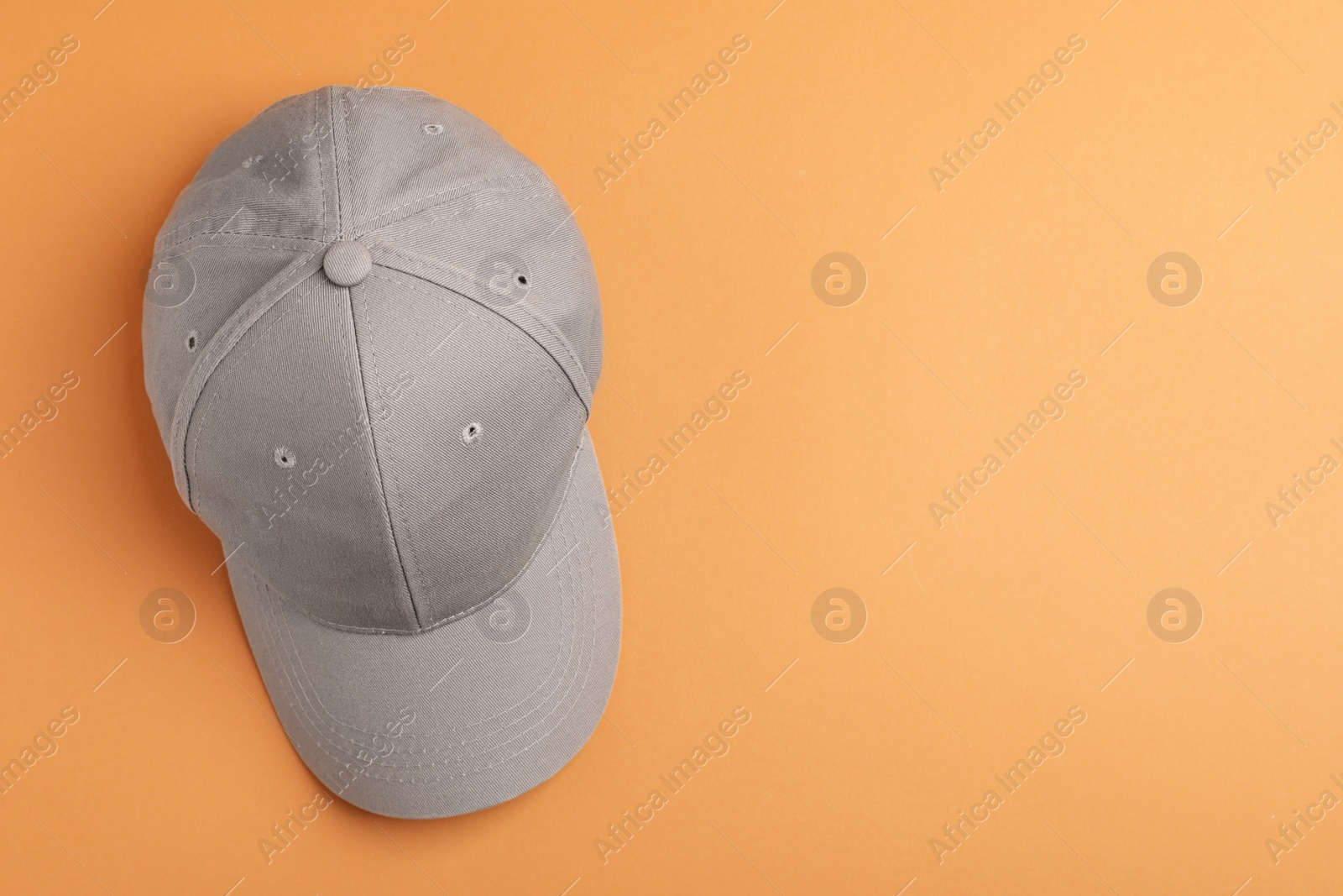Photo of Stylish grey baseball cap on orange background, top view. Space for text
