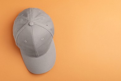 Photo of Stylish grey baseball cap on orange background, top view. Space for text