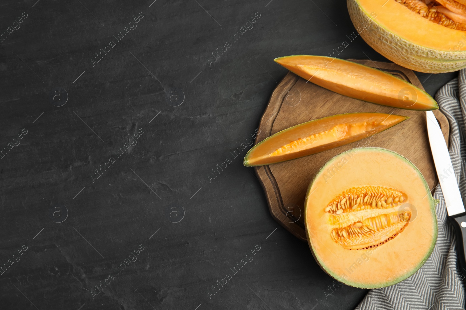 Photo of Tasty fresh melons on black slate table, flat lay. Space for text