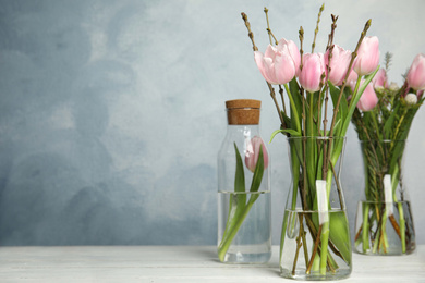 Photo of Beautiful bouquet with spring pink tulips on white table. Space for text